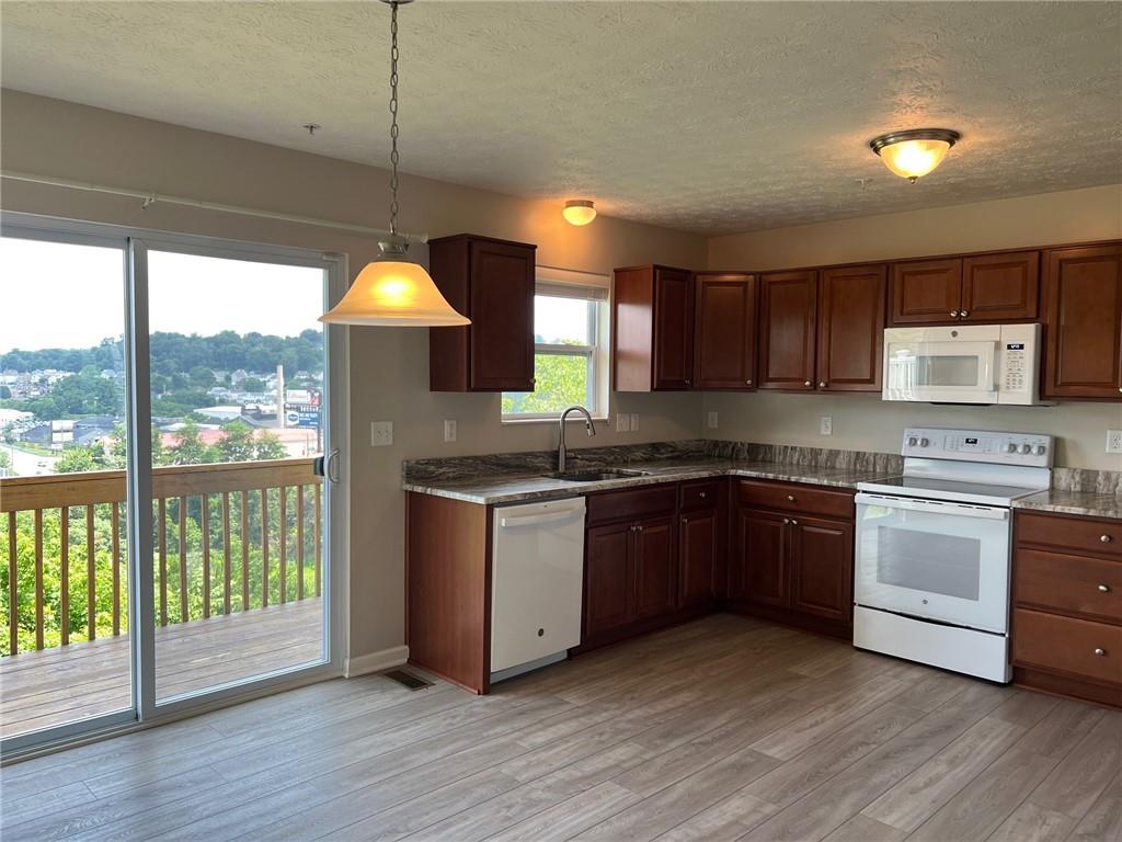 102 Alderwood Drive Greensburg, PA 15601 - Photo 6 of 12 a kitchen with granite countertop wooden floors a stove a sink and a window
