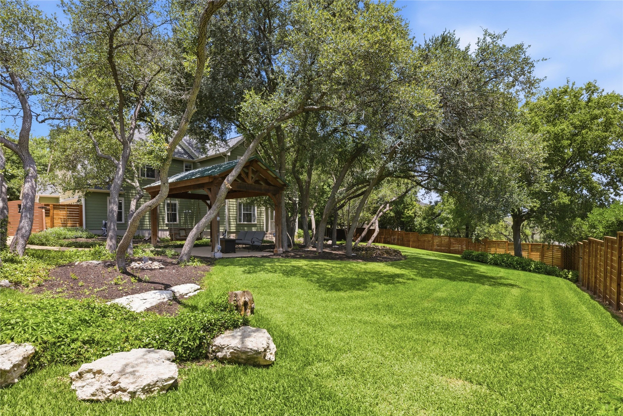 1204 Orlando Road Austin, TX 78733 - Photo 18 of 40 A private backyard oasis features mature shade trees, a covered patio, and a well-maintained lawn.