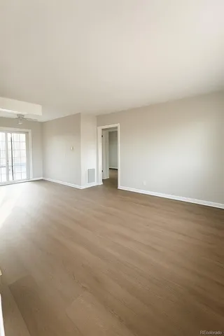 a view of an empty room with wooden floor and a window