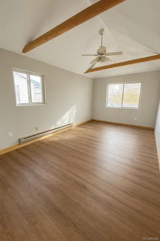 an empty room with wooden floor staircase and windows