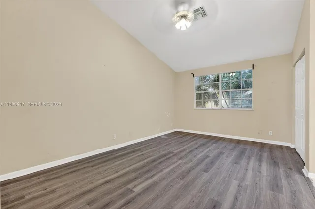 a view of an empty room with wooden floor and a window