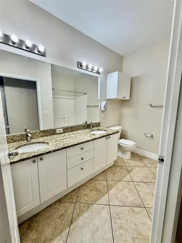 a bathroom with a granite countertop sink a toilet and a mirror