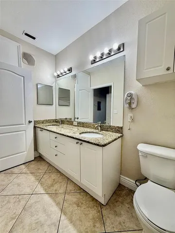 a bathroom with a granite countertop toilet sink and mirror