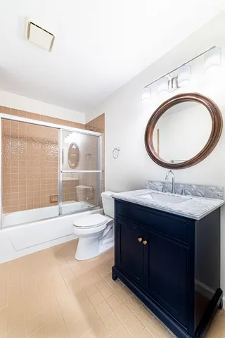 a bathroom with a granite countertop toilet a sink and a mirror