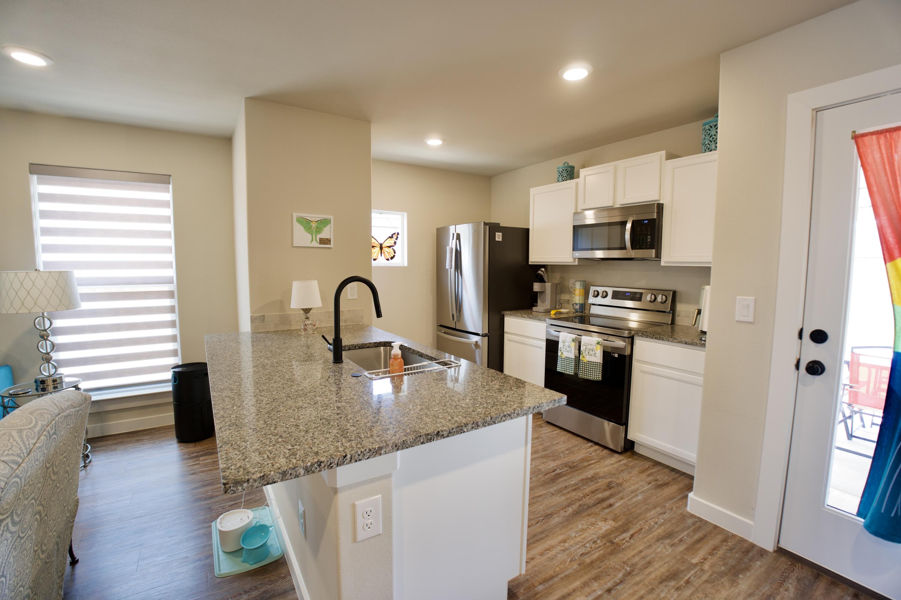 1913 134th Street Lubbock, TX 79423 - Photo 4 of 15 a kitchen with stainless steel appliances granite countertop a sink a stove and a refrigerator