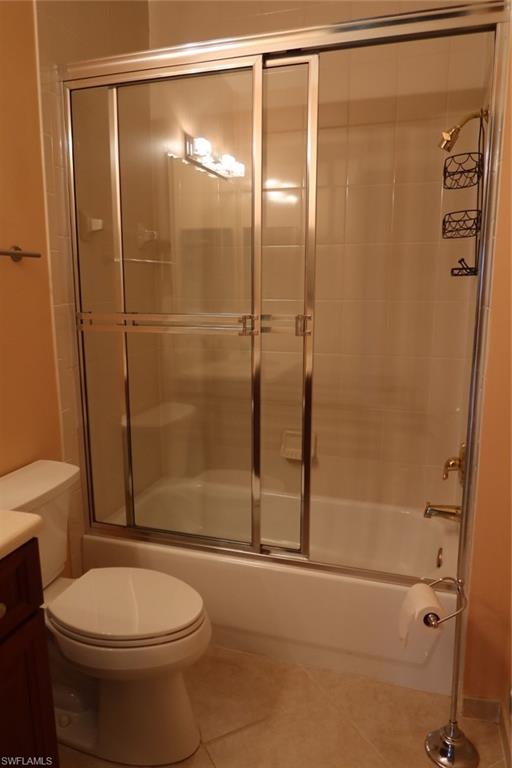7168 Lemuria Circle, Unit 1701 Naples, FL 34109 - Photo 27 of 39 Bathroom featuring a shower-tub combination with sliding glass doors, white tiled walls, and a chrome showerhead