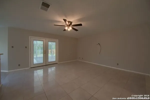 an empty room with chandelier fan and windows