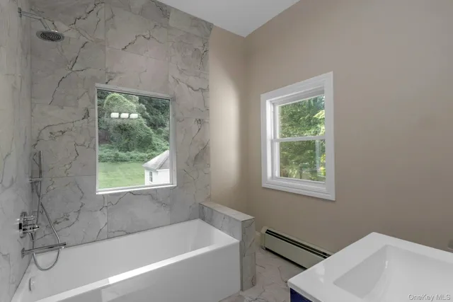 a bathroom with a tub a sink and a window