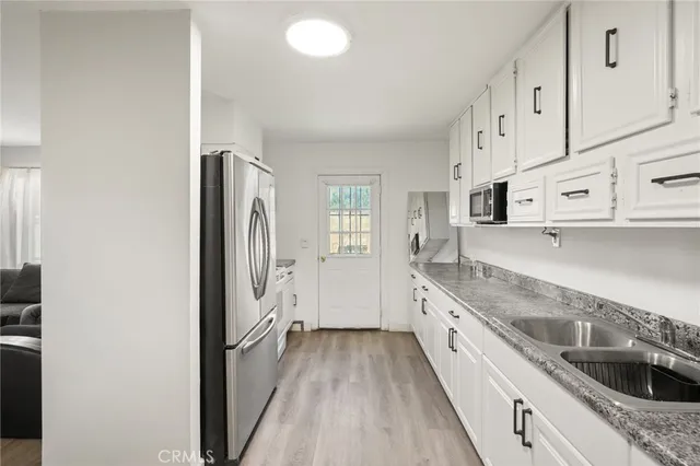 a kitchen with granite countertop a sink stove and refrigerator