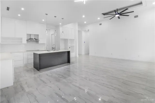 a view of kitchen with kitchen island a sink wooden floor and a refrigerator