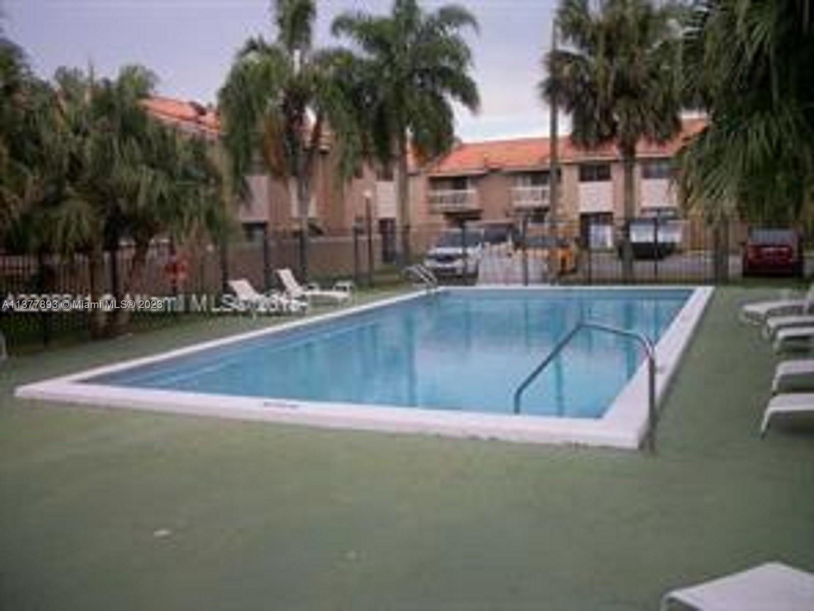 15465 Southwest 80th Street, Unit 2014 Miami, FL 33193 - Photo 23 of 23 a view of a swimming pool with a lawn chairs under palm trees