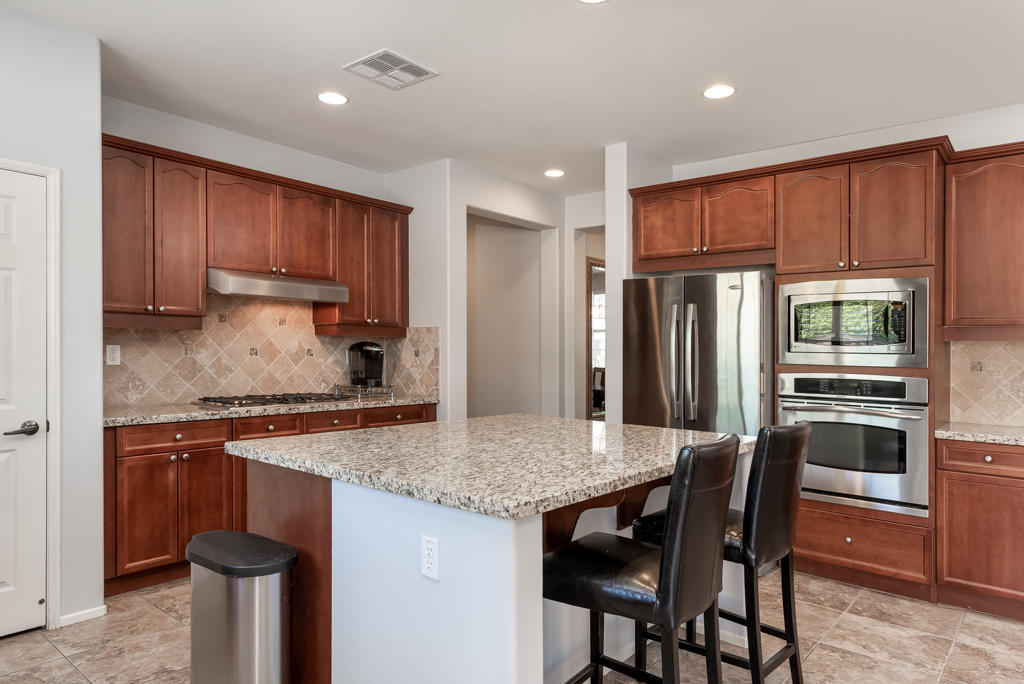 83460 Lone Star Road Indio, CA 92203 - Photo 7 of 40 a kitchen with stainless steel appliances granite countertop a stove a refrigerator a sink a dining table and chairs