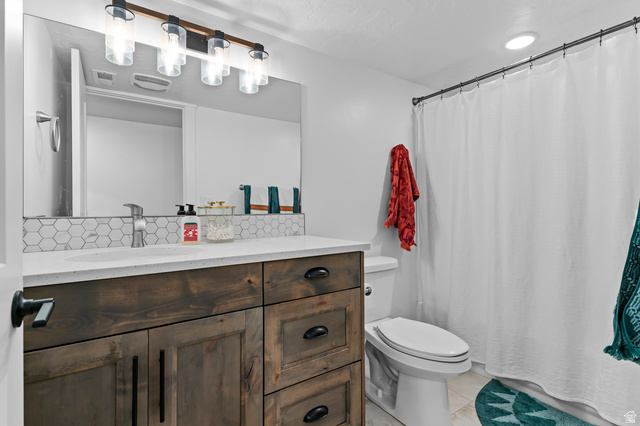 1426 South 1450th Street West Mapleton, UT 84664 - Photo 24 of 50 Bathroom featuring a wood-finish vanity with dark hardware, a white countertop, and a hexagonal tile backsplash