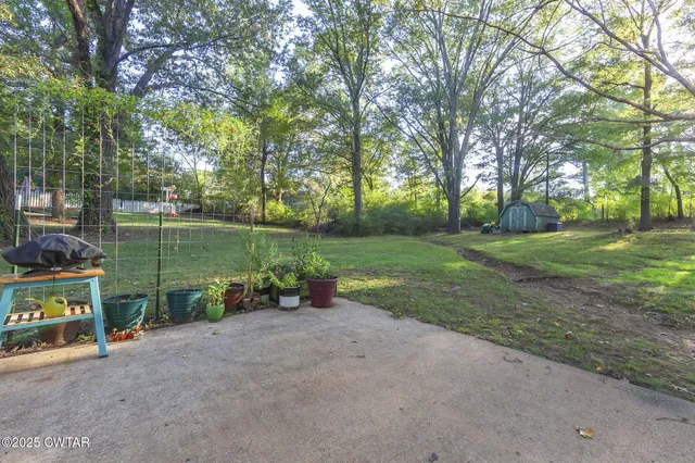 a backyard of a house with large trees and wooden fence