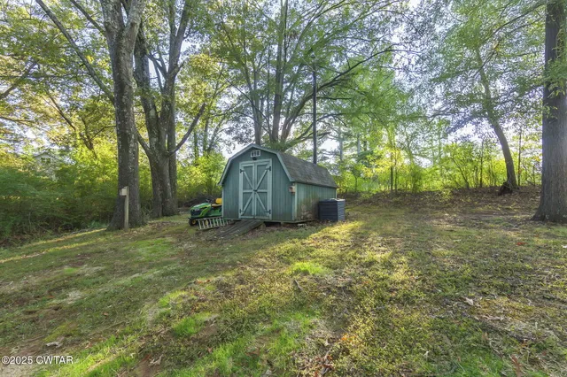 a view of yard with green space and trees in the background