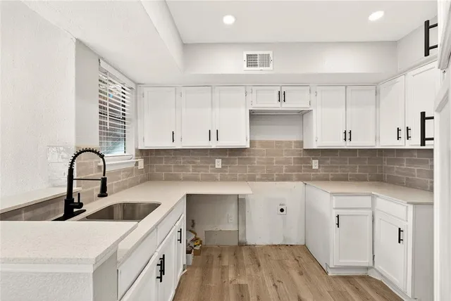 a kitchen with a sink cabinets and wooden floor