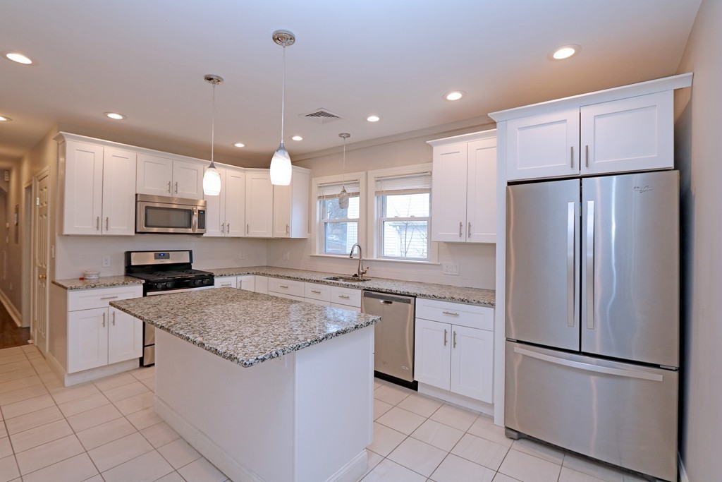 a kitchen with granite countertop stainless steel appliances a refrigerator a stove top oven and a center island