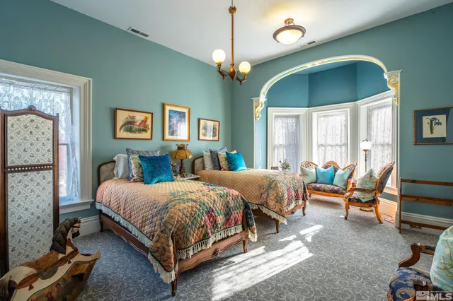 a bedroom with bed a chandelier and a flat tv screen