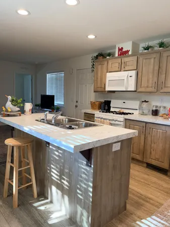 a kitchen with kitchen island granite countertop a sink cabinets and stainless steel appliances