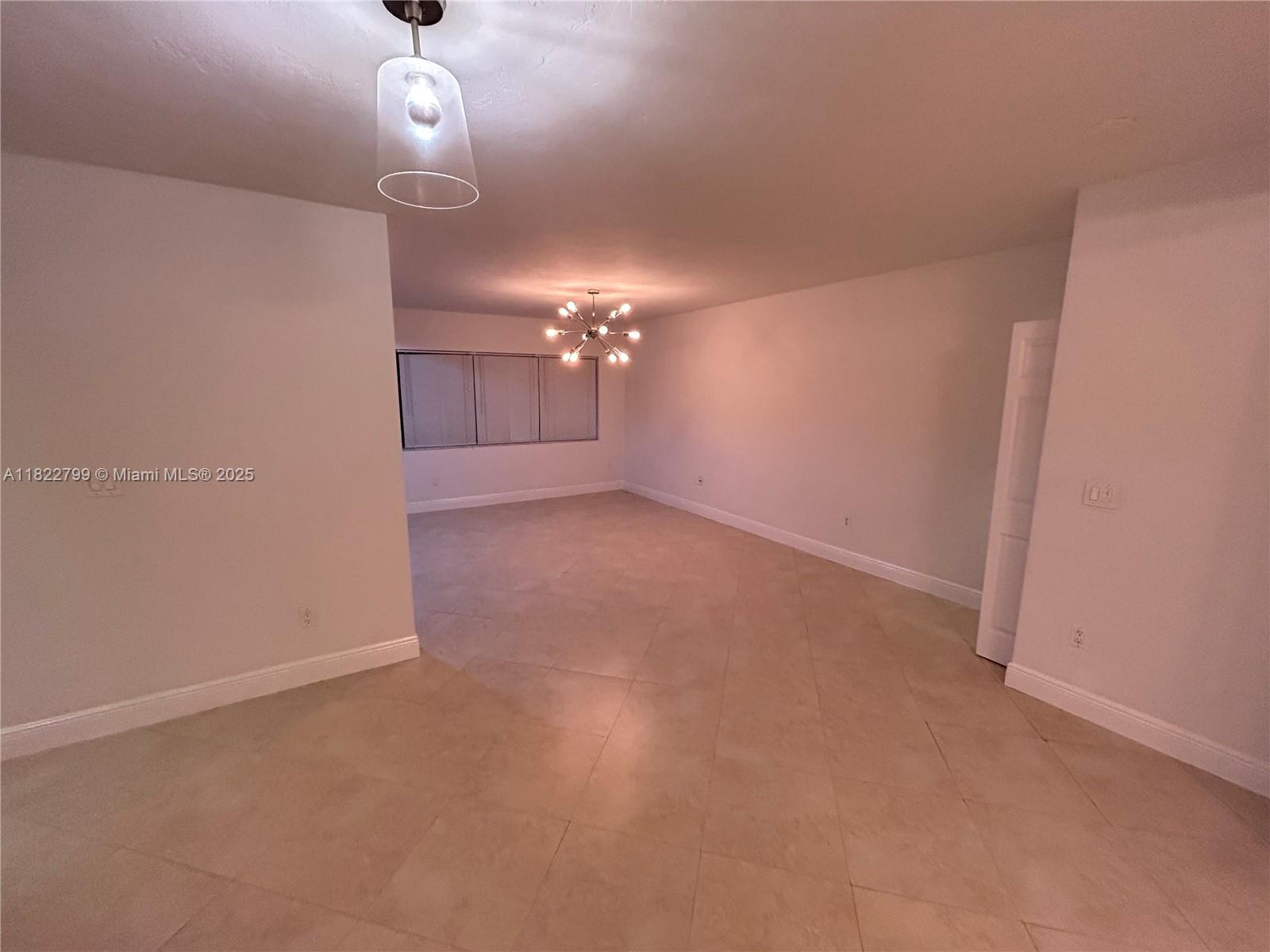 2880 Pine Tree Drive, Unit 1 Miami Beach, FL 33140 - Photo 4 of 13 en empty room with a chandelier fan and window
