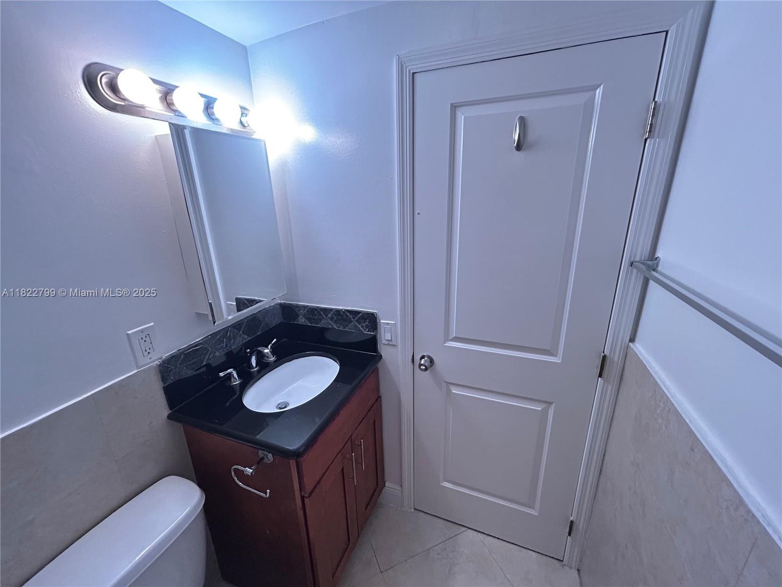 2880 Pine Tree Drive, Unit 1 Miami Beach, FL 33140 - Photo 10 of 13 a bathroom with a granite countertop sink and a mirror