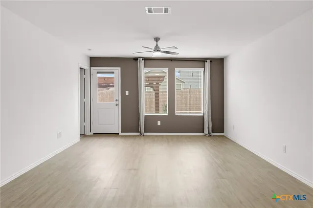 an empty room with wooden floor cabinet and windows