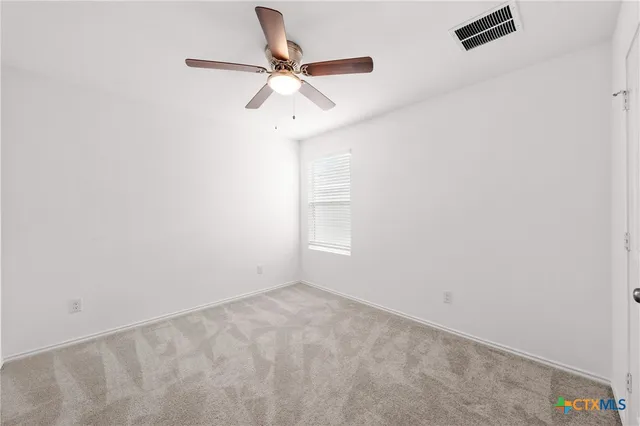 an empty room with a window and a fan