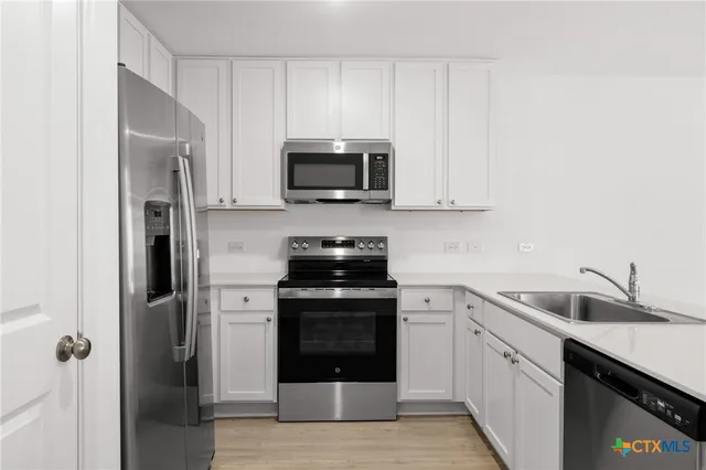 a kitchen with white cabinets and stainless steel appliances