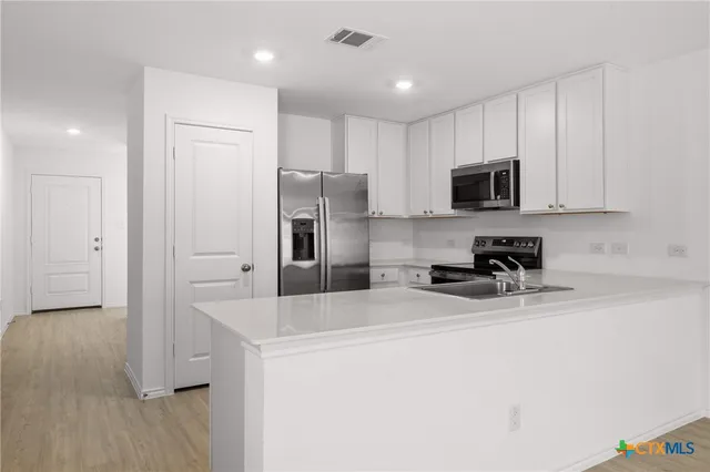 a kitchen with a refrigerator a stove top oven a sink and cabinets