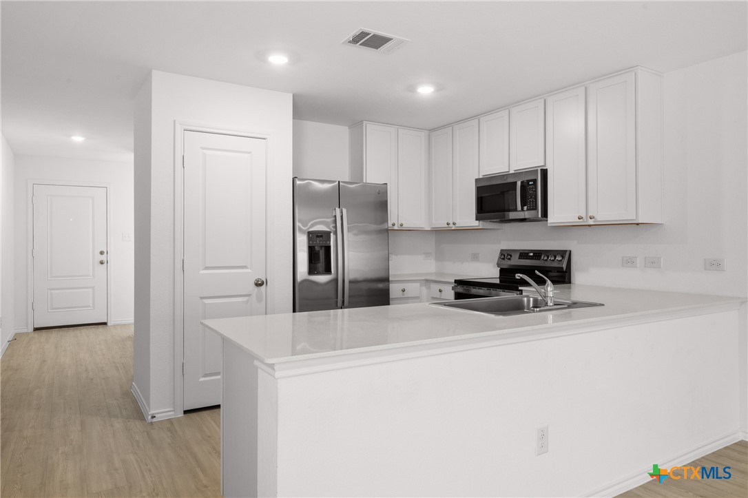 517 Texas Angel Way Jarrell, TX 76537 - Photo 10 of 35 a kitchen with a refrigerator a stove top oven a sink and cabinets
