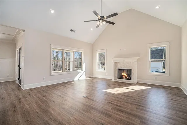 an empty room with wooden floor fireplace and windows