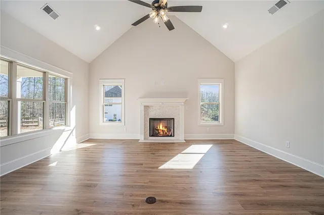an empty room with wooden floor a fireplace and windows