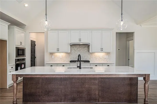 a kitchen with kitchen island granite countertop a sink a center island and stainless steel appliances
