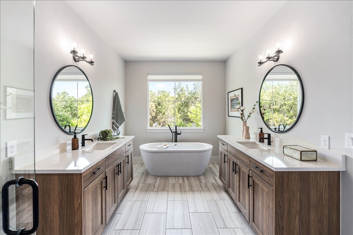 7910 Ryans Way Austin, TX 78726 - Photo 21 of 39 The spa-inspired primary bathroom features a freestanding soaking tub perfectly positioned beneath a large window.