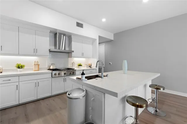 a kitchen with a sink a stove cabinets and wooden floor