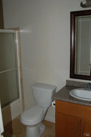 a bathroom with a granite countertop toilet sink and mirror