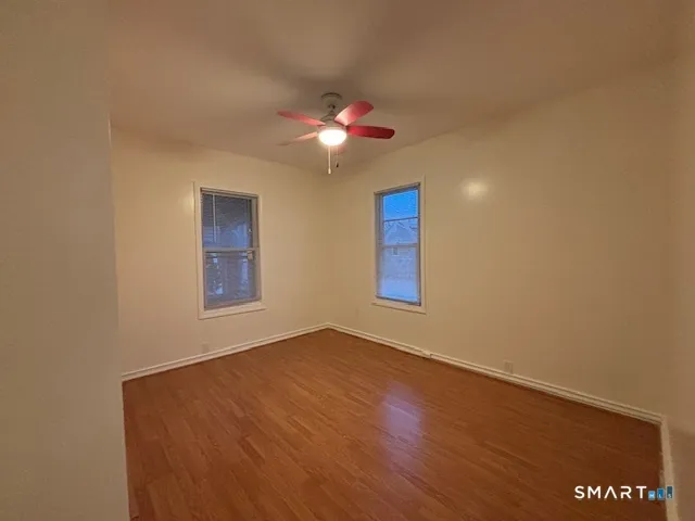 a view of an empty room with window and chandelier fan
