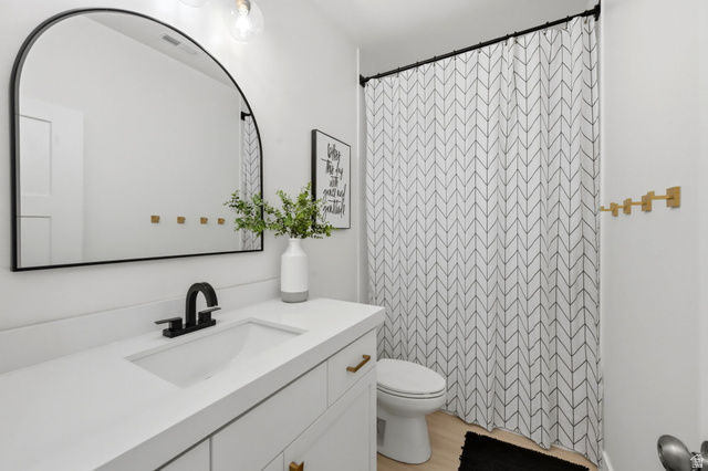 57 McCall Ln. Farmington, UT 84025 - Photo 22 of 36 Bathroom featuring a white vanity with integrated sink, black faucet, and brass-tone hardware