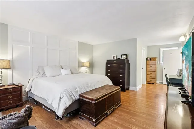 a bedroom with a bed and dresser with wooden floor