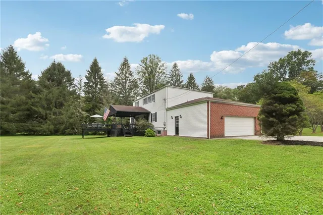 a view of a white house with a big yard and large trees