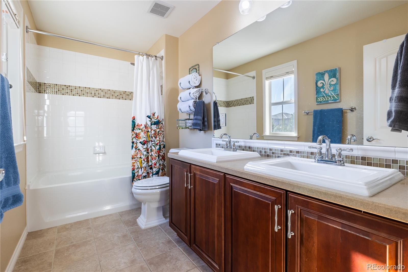 10681 Sundial Rim Road Highlands Ranch, CO 80126 - Photo 27 of 45 a bathroom with a double vanity sink toilet mirror and shower