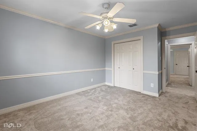 an empty room with a chandelier fan and closet