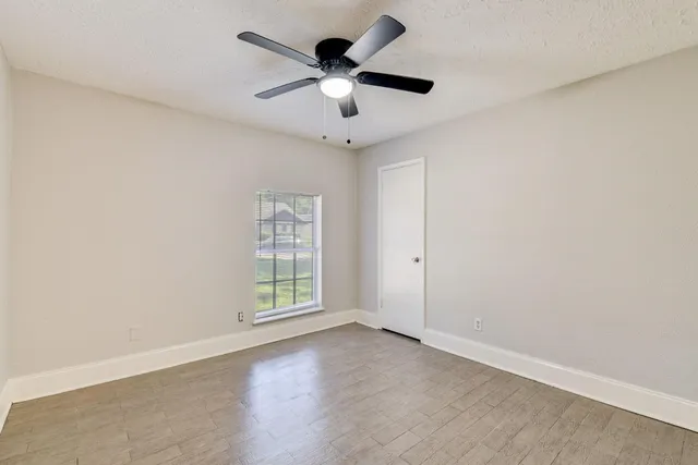 an empty room with ceiling fan and windows