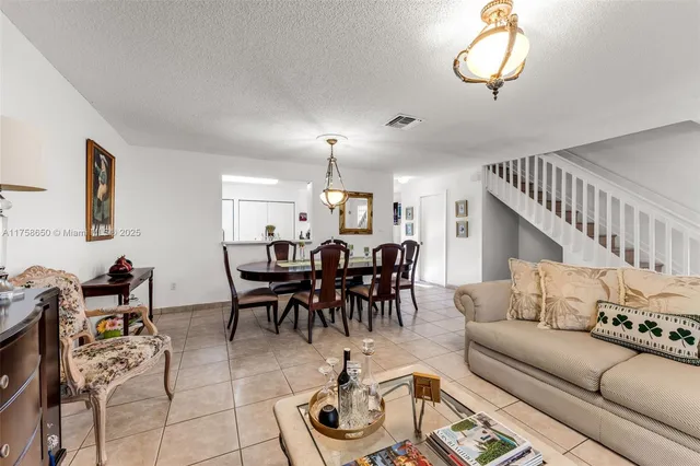 a living room with furniture kitchen view and a chandelier