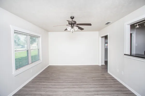 a view of empty room with wooden floor and fan