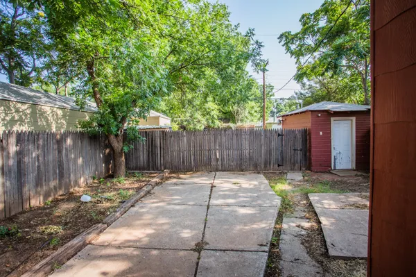 a backyard with table and chairs and a large tree
