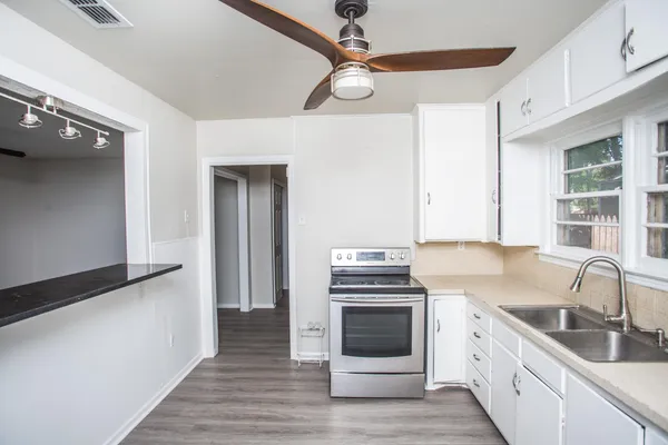 a kitchen with stainless steel appliances white cabinets a sink and a stove