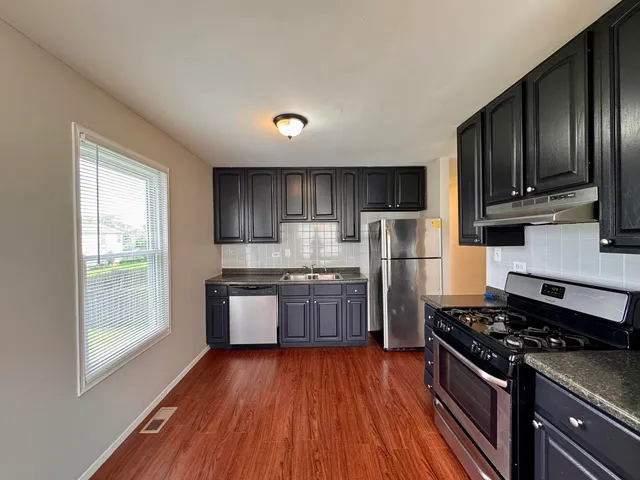 a kitchen with stainless steel appliances granite countertop a stove a refrigerator and wooden cabinets
