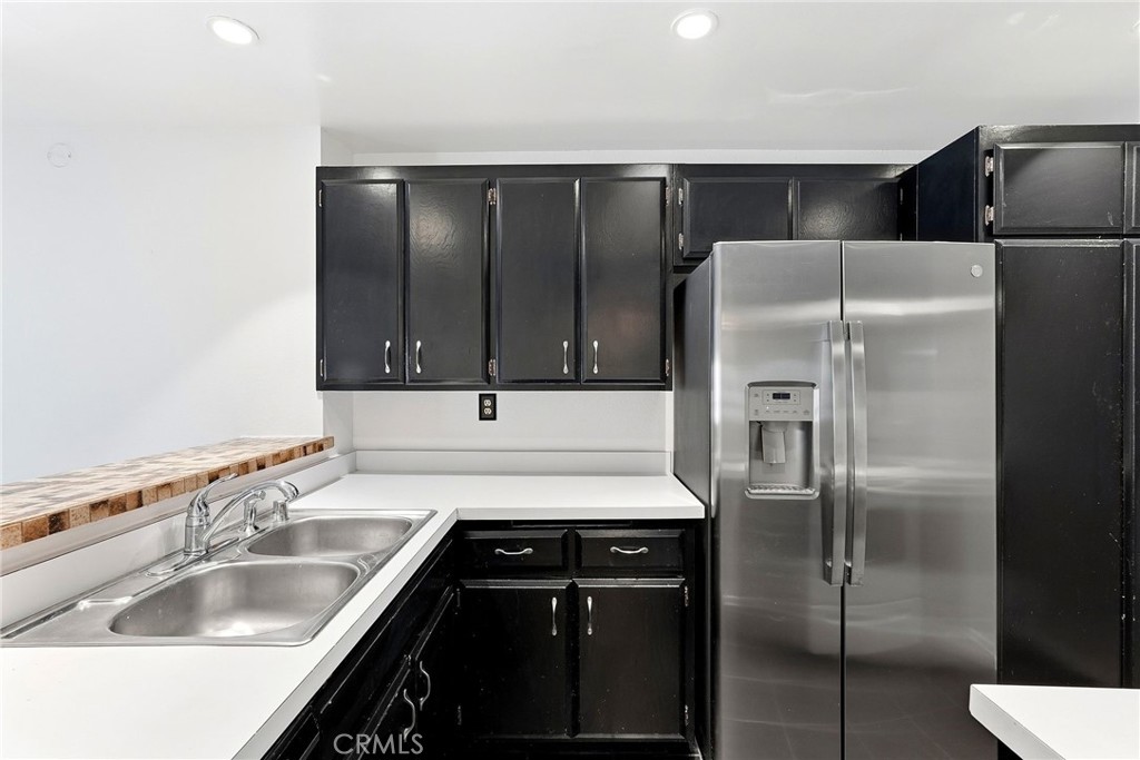 7890 East Spring Street, Unit 11E Long Beach, CA 90815 - Photo 21 of 40 a kitchen with a refrigerator sink and cabinets