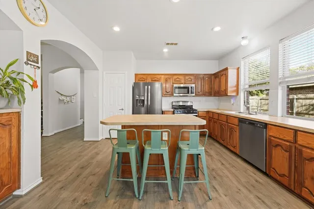a kitchen with stainless steel appliances a dining table chairs and wooden floor